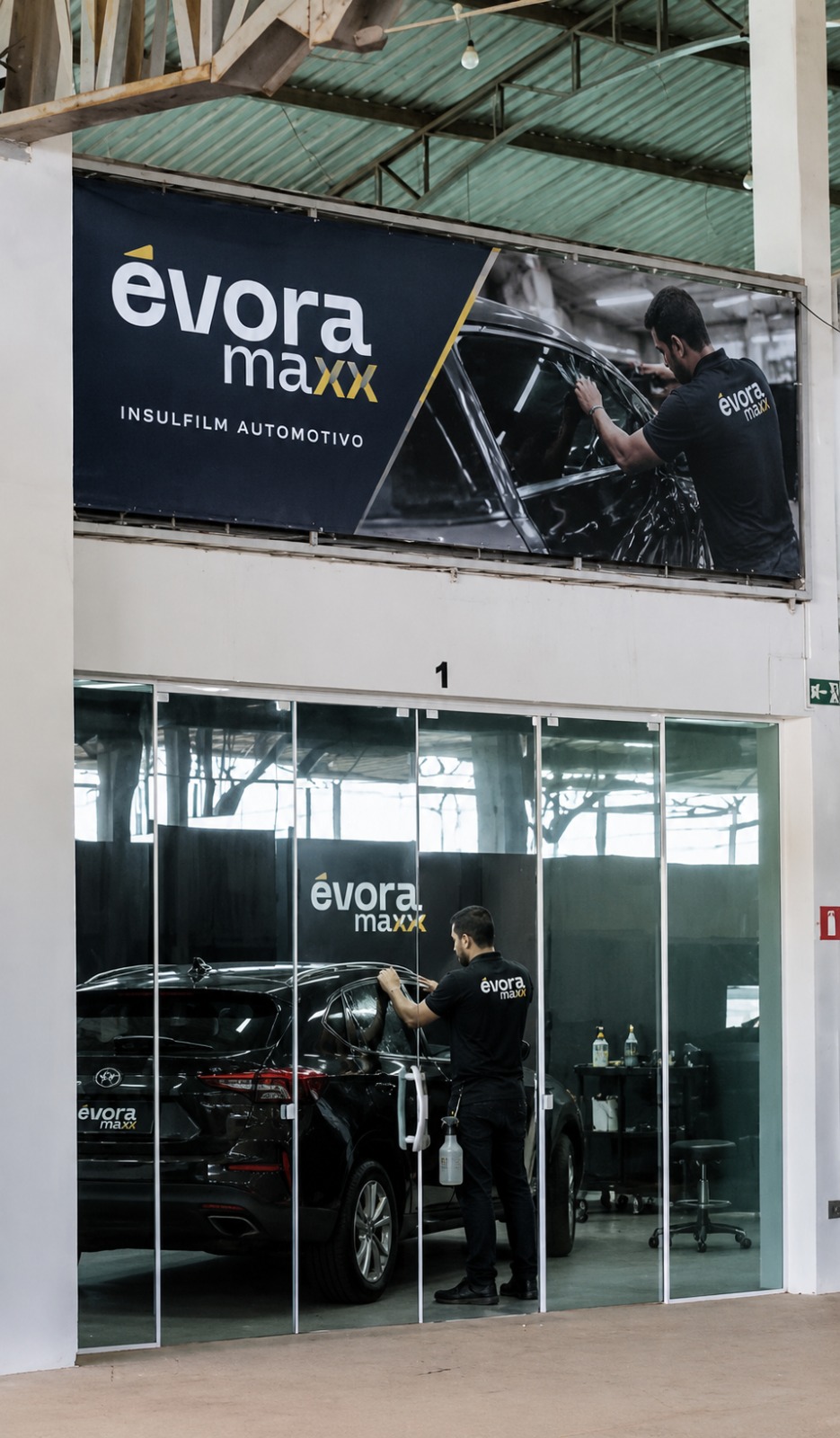 Aplicador Évora Maxx finalizando película em SUV preto dentro da sala envidraçada