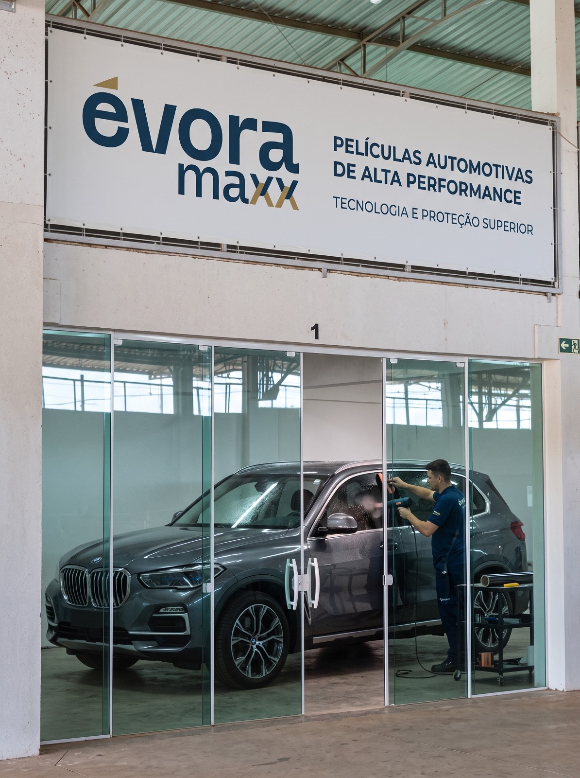 Sala de aplicação Évora Maxx com SUV recebendo película e banner de películas de alta performance